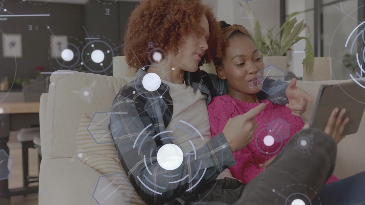 Woman holding tablet and tapping, starting HUD while man leaning and pointing, exploring tech app