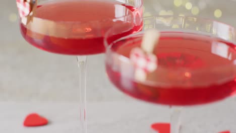 Video-of-two-red-drinks-in-cocktail-glasses-with-hearts,-selective-focus-with-copy-space