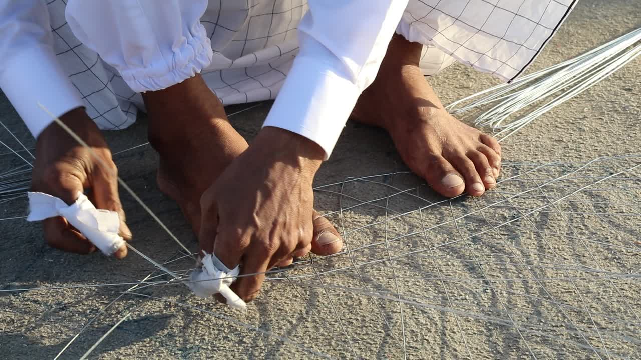 Close-up de mãos e pés construindo uma armadilha de lagosta.