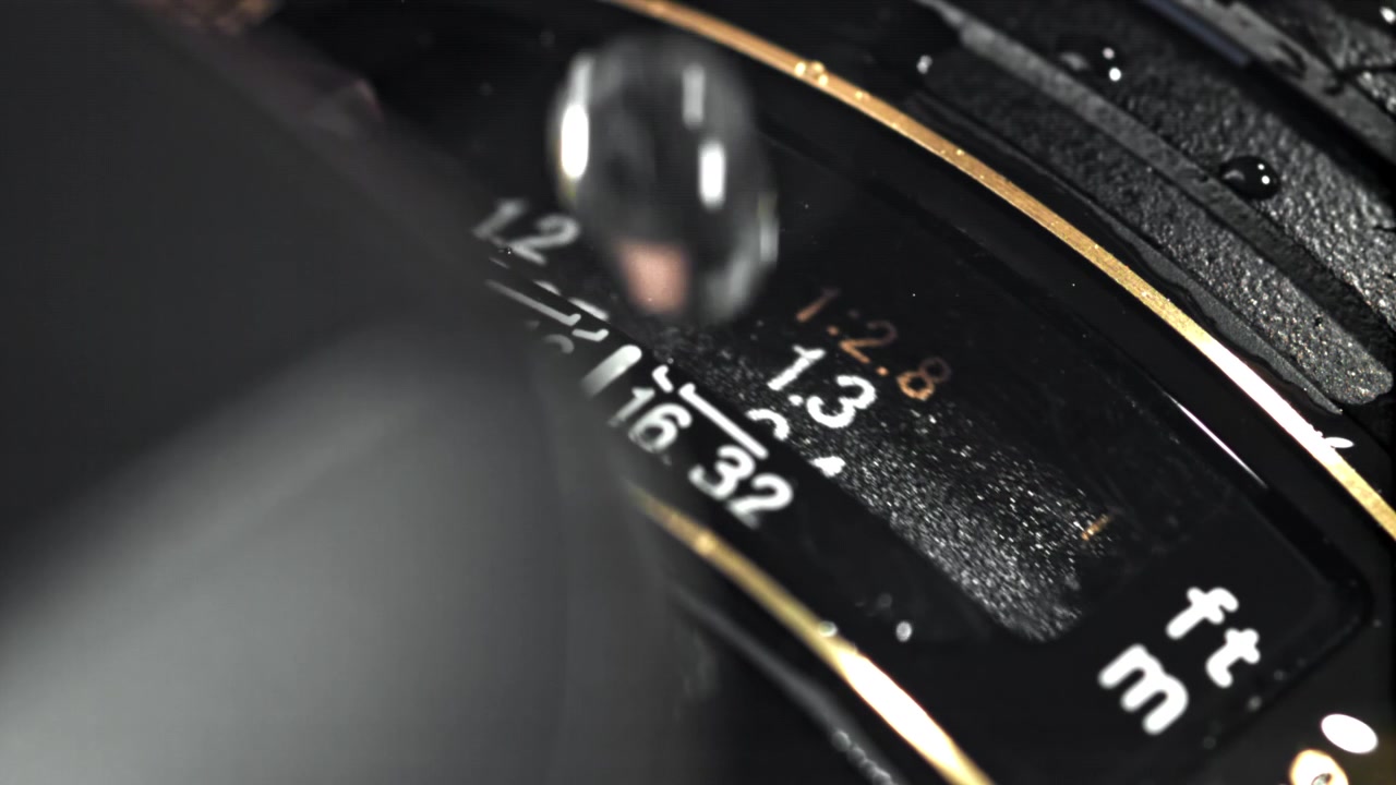 Gocce d'acqua che schizzano al rallentatore sull'obiettivo di una fotocamera