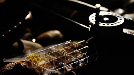 fly fishing rod, reel and fishing bait on rock