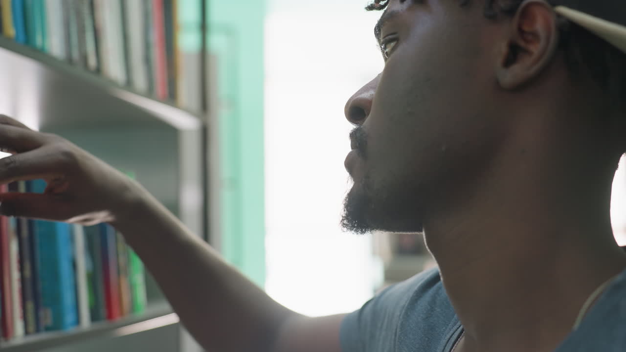 Focused close up of African student returning book to shelf in library, showing concentration and detail against blurred background of bookshelves and soft natural light