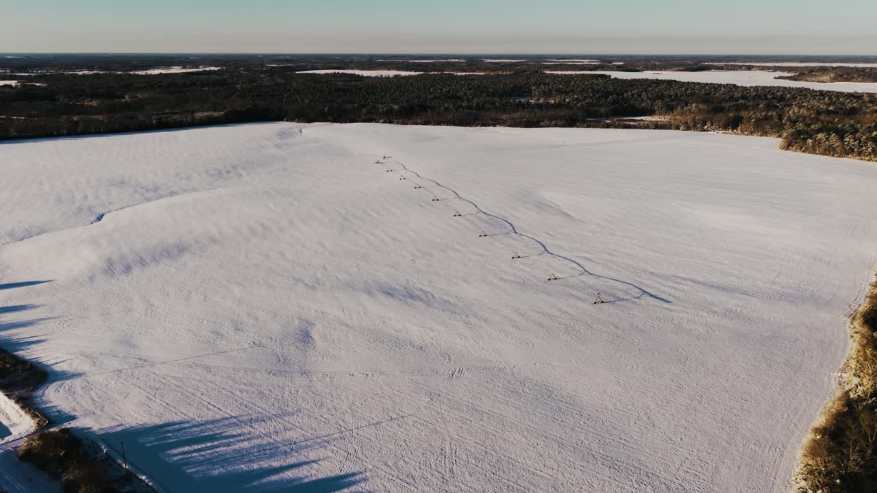 Aerial view of a vast snow-covered field featuring a pivot irrigation system. The drone executes a smooth right oscillating movement, capturing South Georgia's rare snowfall.