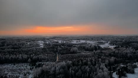 aerial drone hyperlapse of vibrant winter sunset over a frozen snow covered forest in countryside landscape. hoar on trees.
