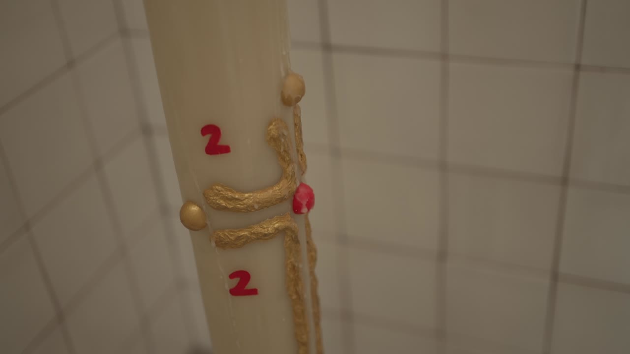 vela de pascua intrincadamente decorada con detalles rojos y dorados en un fondo de azulejos