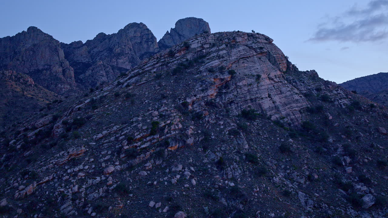Drone shot panning across desert landscape near sunset with dramatic lighting hitting rock face