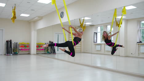 the concept of sports for a healthy lifestyle. the girl has been aerology of antigravity relaxes and swings on the canvas in a white room