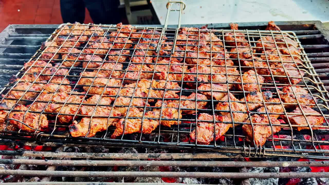 Close-up of marinated meat sizzling on a wire rack over hot coals during outdoor grilling