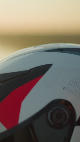 un primer plano de una mano con una pulsera verde, limpiando suavemente un casco de motocicleta