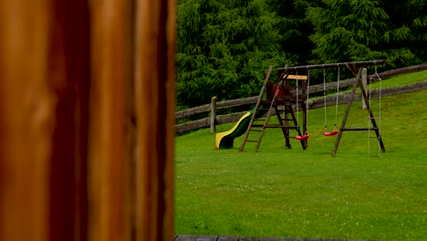 un parque infantil vacío con columpio y tobogán en una idílica cabaña de montaña en austria