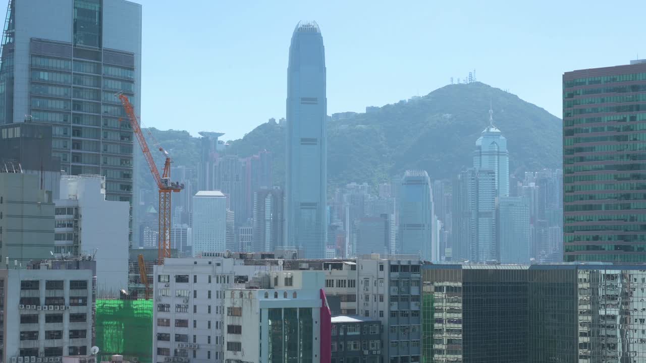 A row of buildings is seen in the foreground, from Kowloon district side, as the Hong Kong island skyline rises above them in the background.