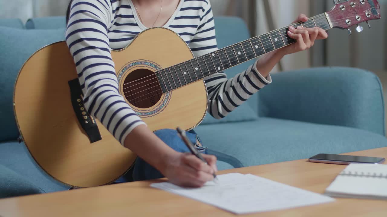 mujer tocando la guitarra acústica y escribiendo canciones