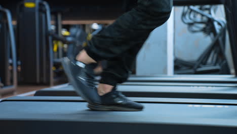 man training in sport club. close up athletic feet running on treadmill in fitness gym