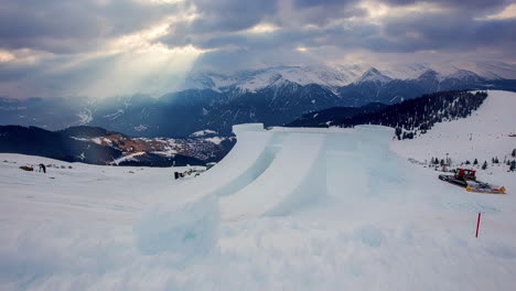 Zeitraffer-Einer-Skisprungschanze,-Die-Von-Maschinen-Geglättet-Wird,-Mit-Wunderschönen-Sonnenstrahlen-Durch-Die-Wolken-Am-Himmel