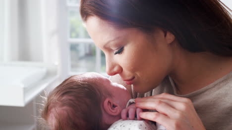 Loving-Mother-Cuddling-Sleeping-Newborn-Baby-Boy-At-Home