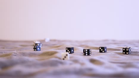 rolling black and white dice together onto grey felt in extreme slow motion