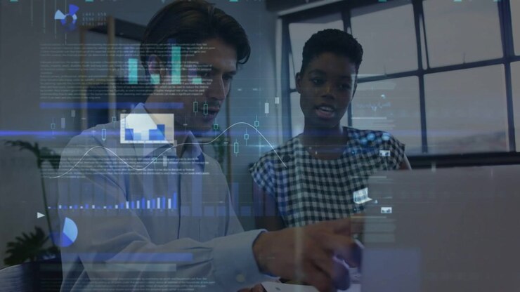 Kollegager udveksler blikke, læner sig ind over bærbar computer og manipulerer animerede diagrammer til dataanalyse.
