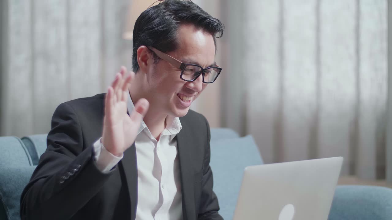 재과 쇼트를 입은 아시아 사업가가가 집에서 노트북으로 비디오 통화를 하고 있습니다.