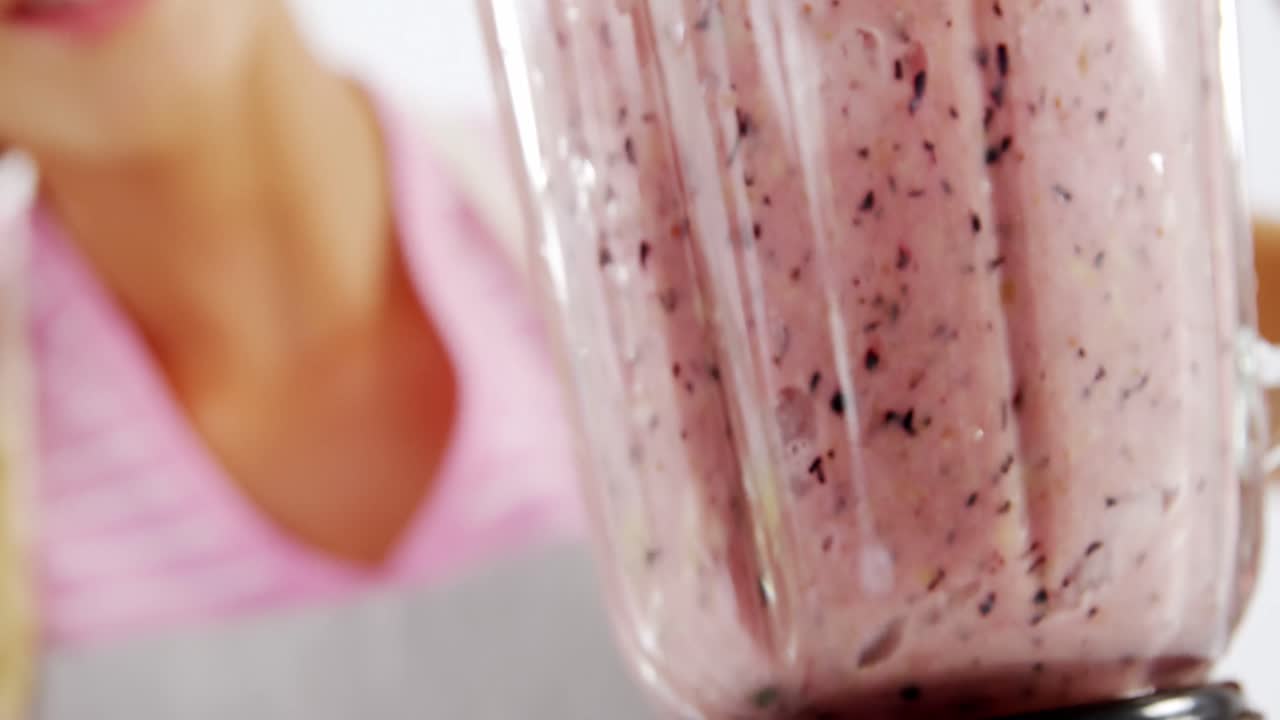 mujer preparando un batido contra un fondo blanco