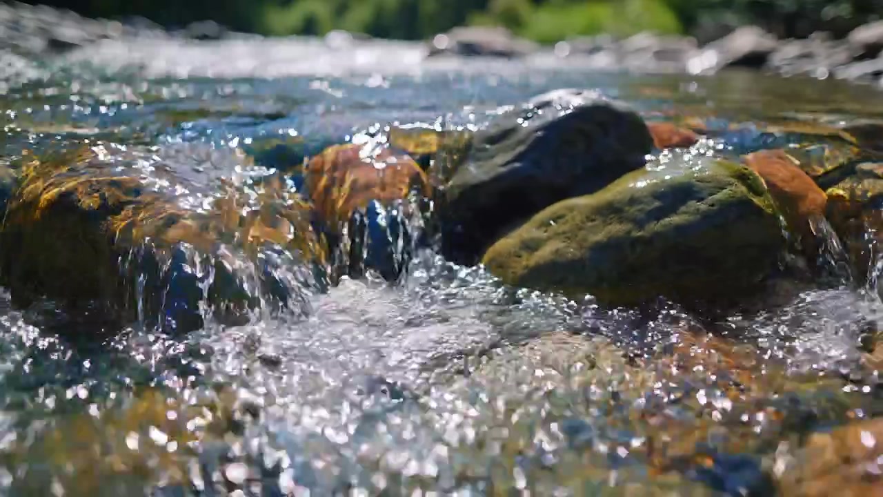 Primo piano di acqua limpida che scorre su ciottoli di fiume levigati.