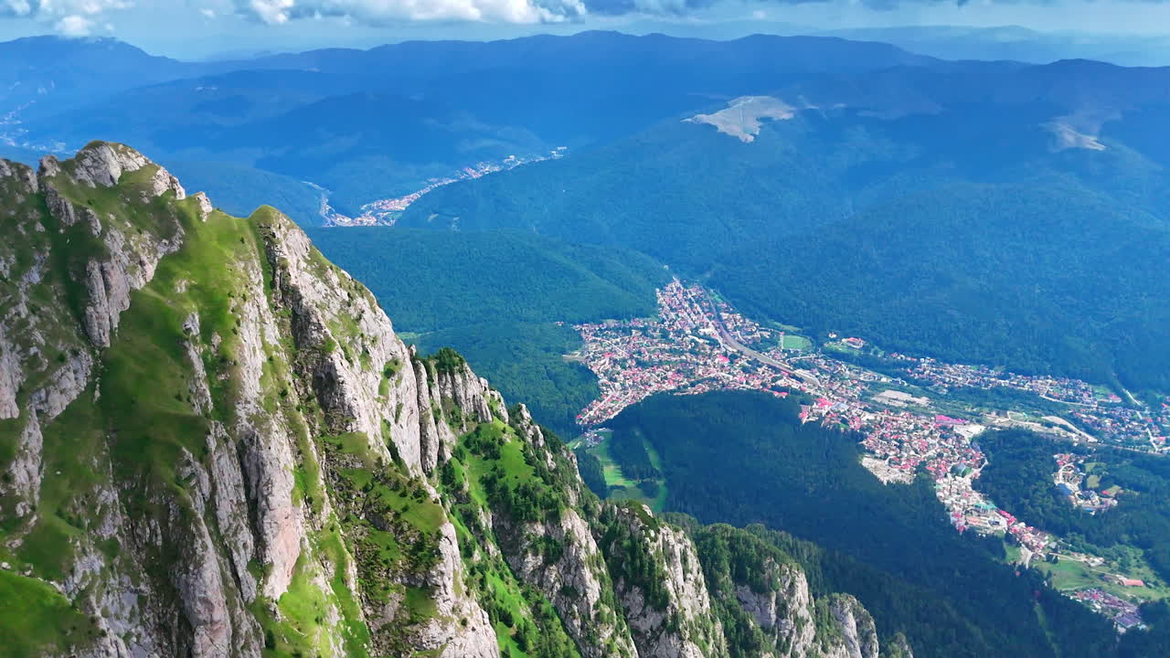 Stunning mountain view, lively town. Breathtaking view of rugged mountains overlooking a colorful town nestled in the valley under a bright sky