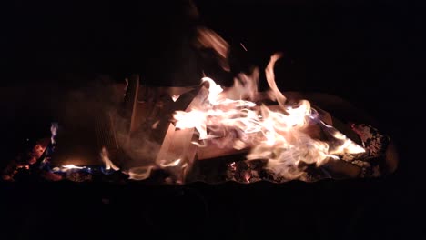 bonfire with wood fuel burns fast giving off heat and light on the incandescent embers in the background, blocked shot in the foreground in the dark of night, galicia, spain