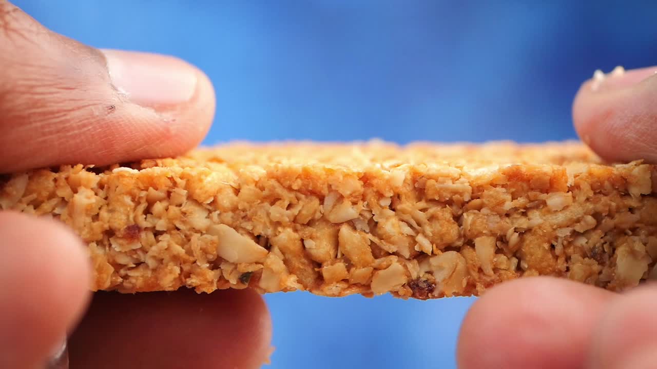 Close-up of a cereal bar held by fingers