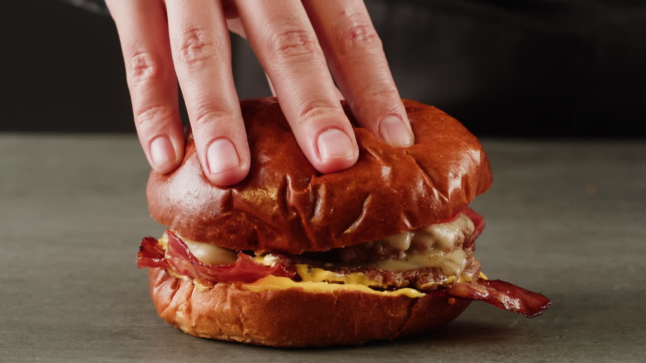 Hand Placing Top Bun on Gourmet Burger