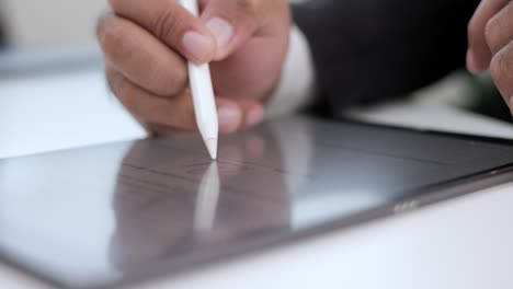 close up businessman hand working electronic signature on tablet by stylus. write business agreement of contract. man signing contract on tablet. business and technology concept.