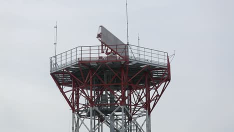 red radar tower against overcast sky, intricate metal structure, modern communication