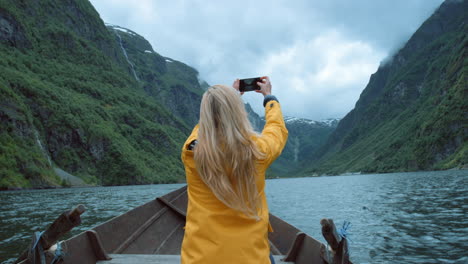 woman taking a picture from a wooden boat in a norwegian fjord