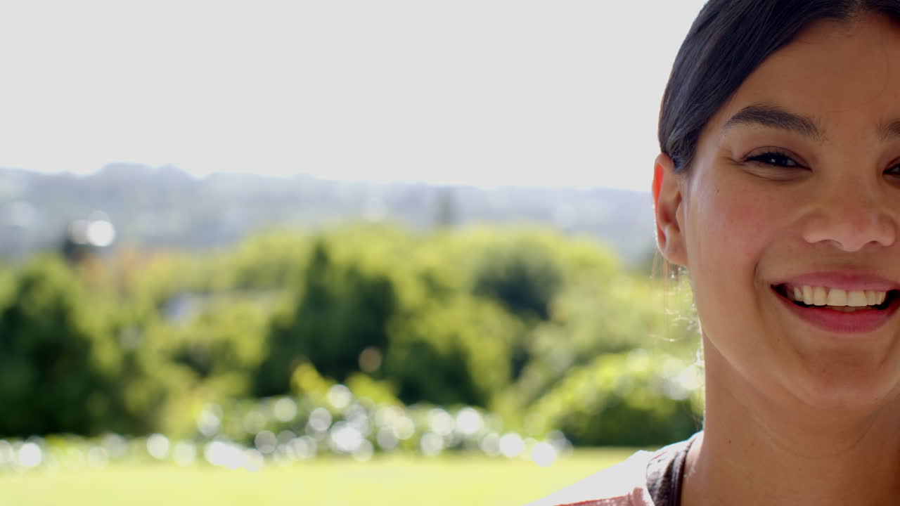 Smiling woman enjoying sunny day outdoors with lush green background, copy space
