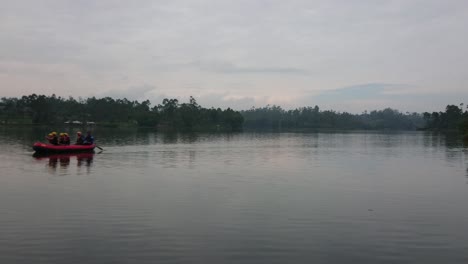 the crew is equipped on a inflatable rafting rubber boat on lake water surface at morning with beautiful view of nature around the lake