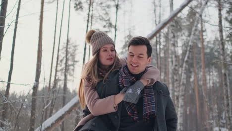 Happy-Couple-is-Playing-Winter-Game-Outside-Enjoying-Sunlight-and-Warm-Winter-Weather-in-the-Mountains.-Strong-Boy-is-Carrying-Girlfriend-on-His-Shoulders-and-Whirls-Her