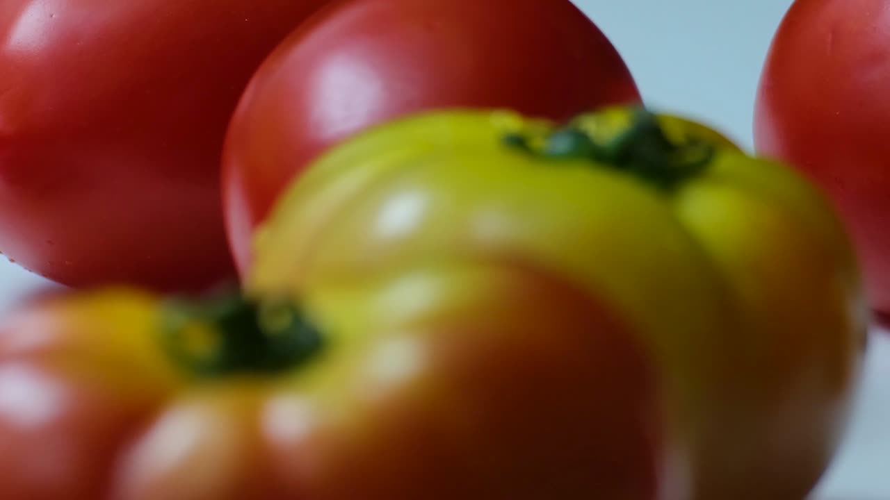 disparo en primer plano de tomates en diferentes colores y luz suave desde el lado izquierdo y fondo blanco