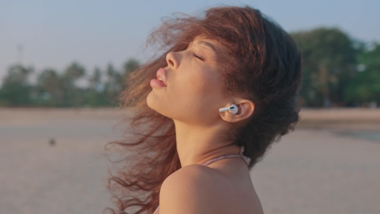 Woman enjoying the beach sunset with earbuds