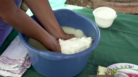 mujer indígena de costa rica presionando cuajada en un balde para extraer bolas de queso, primer plano de mano