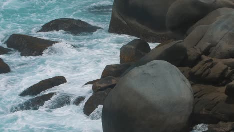 Espumosas-Olas-De-Agua-Chocando-Contra-Las-Rocas-En-La-Playa-A-Cámara-Lenta-En-El-Parque-Tayrona,-Colombia