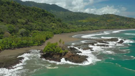 Rock-outcrop-with-green-trees-on-tropical-shore-of-Costa-Rica,-Amancio