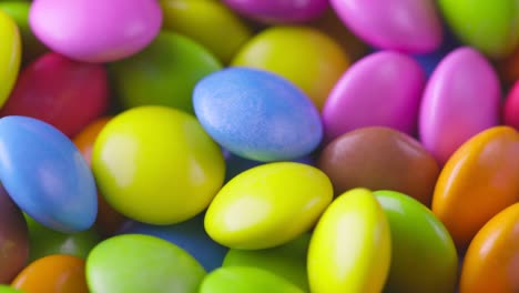 movimiento lento de primer plano de caramelos de chocolate redondos de colores, dragee. rotación y caída de caramellos de chocolate multicolores