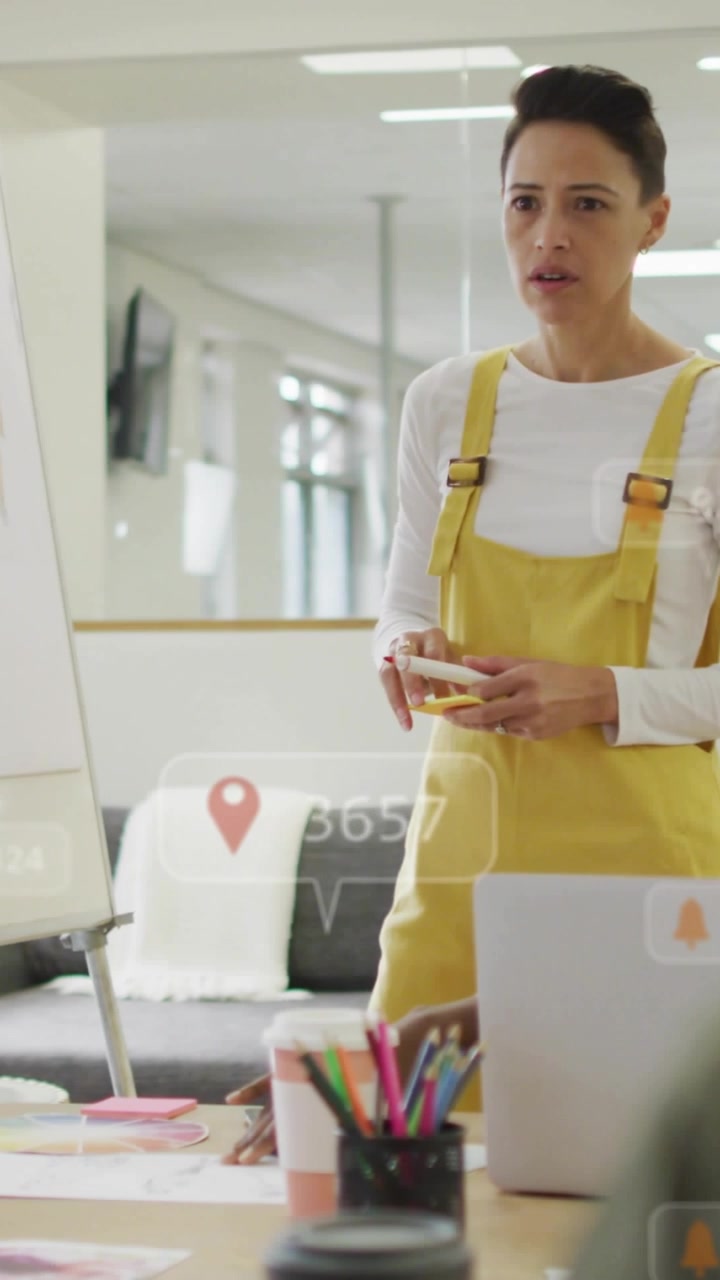 Vertical video: Female presenter tapping phone at design meeting, causing AR overlays updating data