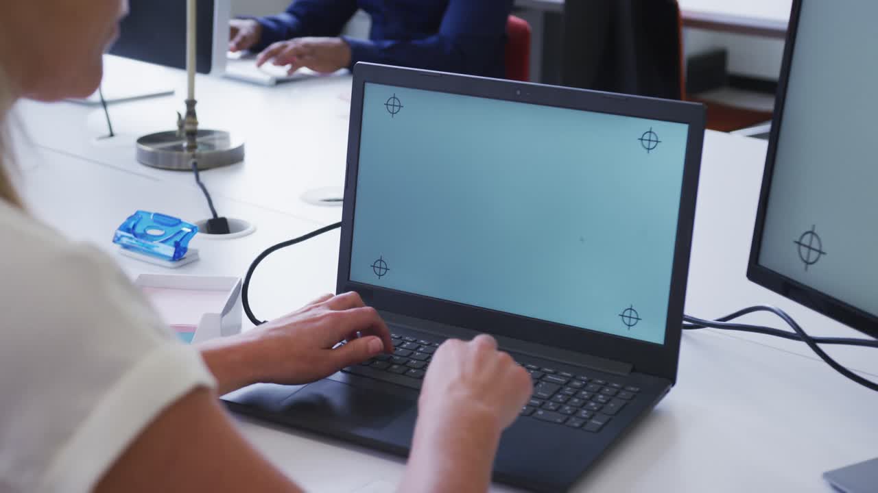 manos de una mujer de negocios caucásica usando una computadora portátil en el escritorio de la oficina