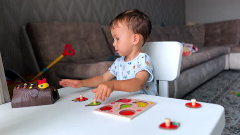 adorable baby boy playing peacefully in his room. kid sits at the desk solving puzzles.