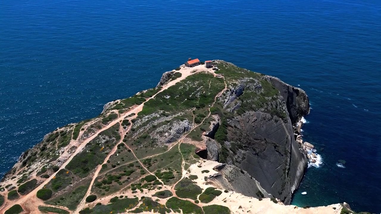 Veduta aerea degli edifici del Farol do Cabo Espichel su un ripido bordo di scogliera in Portogallo. Scenografico patrimonio marittimo e costa oceanica blu.