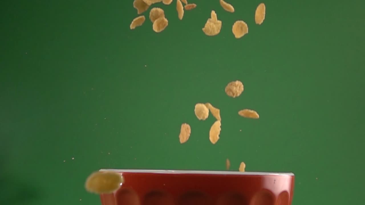 Fiocchi di mais che cadono lentamente su un piatto su uno sfondo chroma key