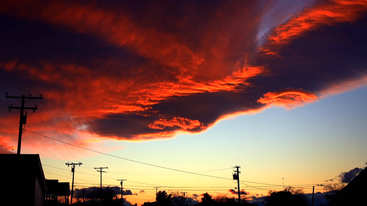 Zeitrafferaufnahme von Wolken, die nach Sonnenuntergang in feurigen, orangefarbenen und roten Lichtern erstrahlen. Die dramatischen Wolken erzeugen eine stimmungsvolle, unheilvolle und atmosphärische Szene mit subtilen Bewegungen.