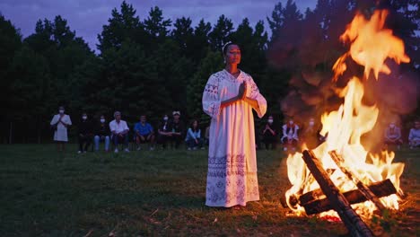 woman in ceremony around campfire at dusk