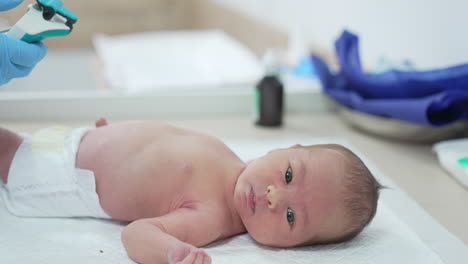 doctor performs medical procedure to an infant. newborn baby lying on hospital table. doctor uses modern medical appliance for treating baby in clinic.