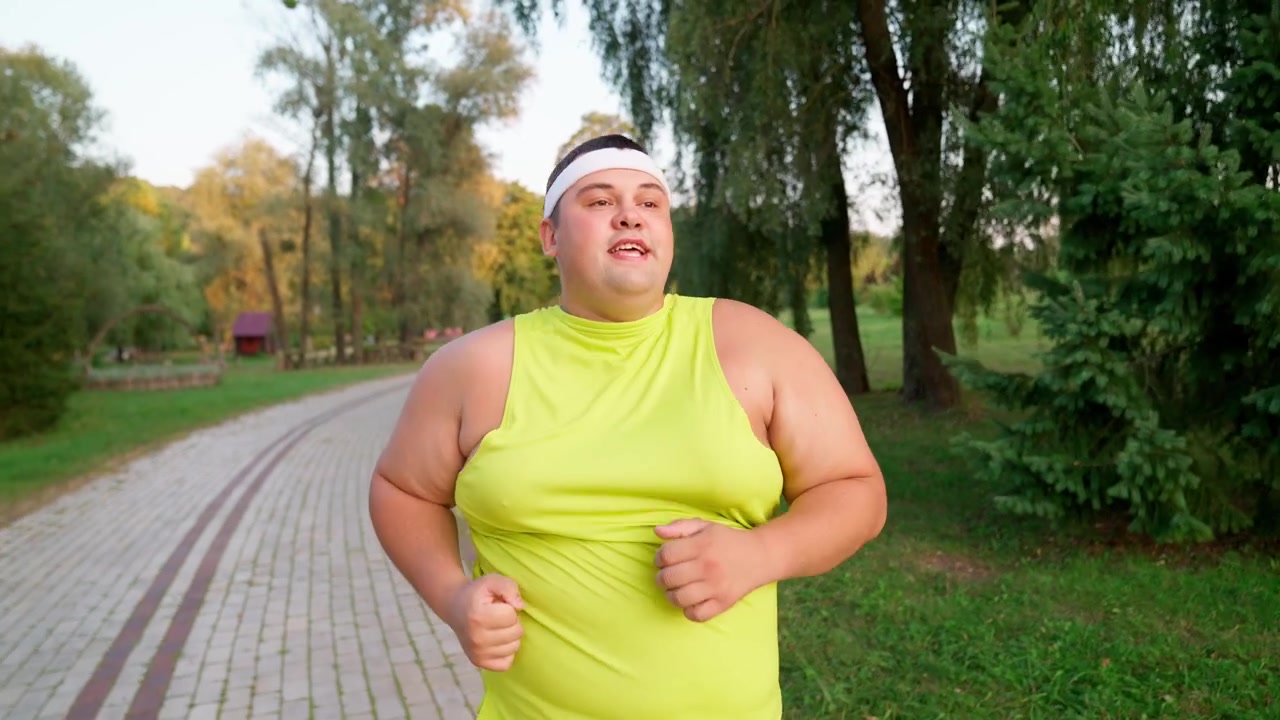Uomo sovrappeso che corre con determinazione in un parco.