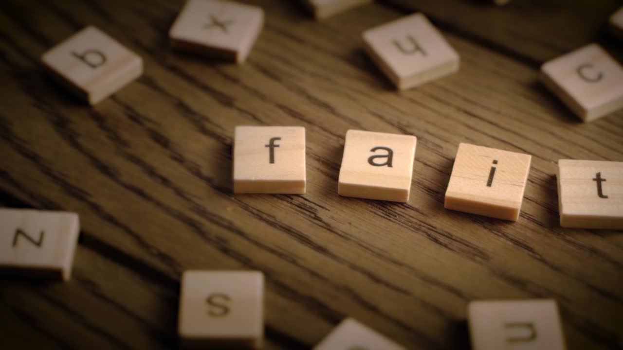 Wooden tiles spell the word faith as the camera pans across a rustic wood surface with soft cinematic lighting.